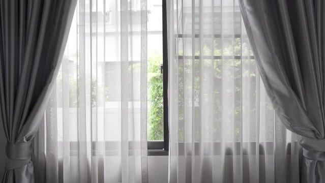 Beautiful curtains on window blured green tree in backyard garden, stylish room interior design.