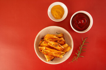 Delicious flatlay topview Fried Cassava in Handcrafted White Ceramic Bowl on Red Studio Background with Ketchup and mustard