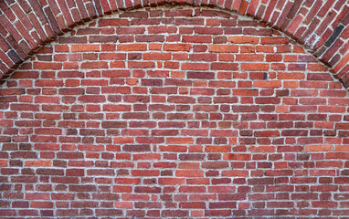 Texture of an old red brick wall with the semicircular arch in brickwork as an old-fashioned architectural background