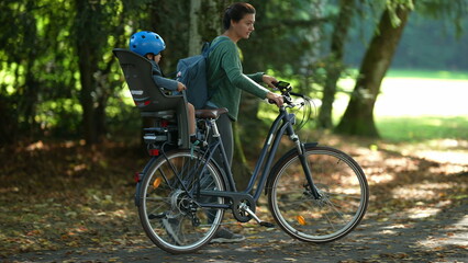 Naklejka premium Parent carries bicycle with child in bike back seat