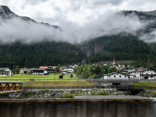 Obraz premium A small village in the Austrian countryside with foggy clouds and forested hilles