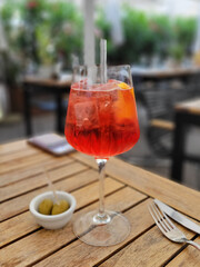 A glass of aperol spritz on a dinner table at happy hour