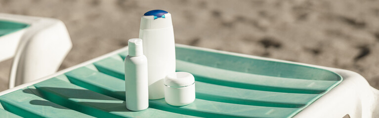 Suntan product bottles on the summer beach. Sunscreen on deck chair outdoors at beach resort