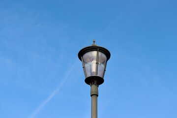 Fototapeta na wymiar The black metal light post with the blue sky background.