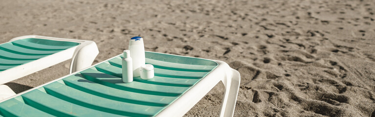 Sunscreen products on deck chair outdoors at empty beach resort