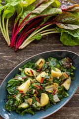 Blitva dish made with boiled potatoes, Swiss chard, garlic and olive oil. Fresh beet leaves on wooden rustic table.