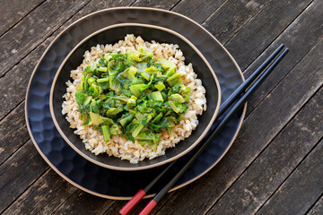 Brown rice topped with stir fry leaves of lettuce  and chicory.