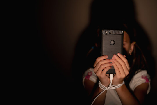 Young child girl playing smartphones during night time. She is chatting with her friend. Using phone in low light is impact to eyes. Health and gadget addiction concept. Copy space for text.