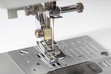 Modern white sewing machine presser foot closeup, macro. Sewing equipment, work tool for atelier business, manufacturing, occupation.