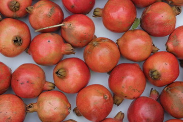 Fototapeta na wymiar Many ripe red pomegranates. Group of pomegranates on a white object