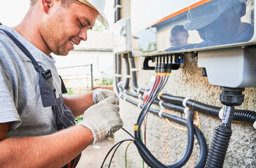 Man electrician installing solar panel system. Technician in helmet and gloves making electrical...