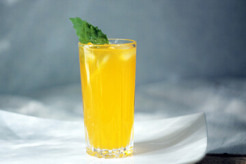 Glass with lemonade or mojito cocktail with lemon and mint, cold refreshing drink or iced drink on shimmering blue background with glow. Copy space