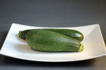 Zucchini on a white plate, space for inscription