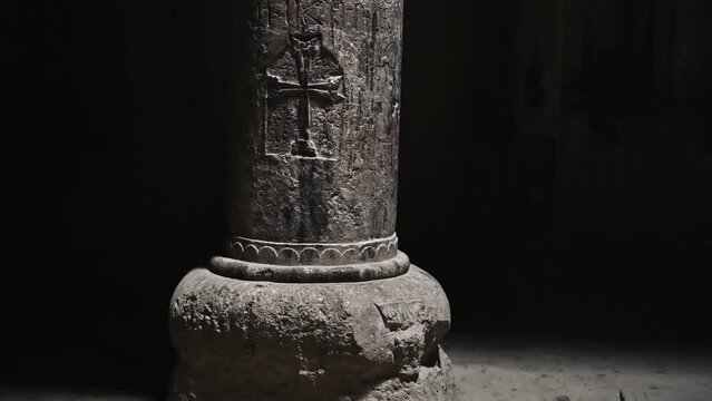The columns of the ancient geghard monastery temple, illuminated through the windows, are carved with religious symbols on the walls.