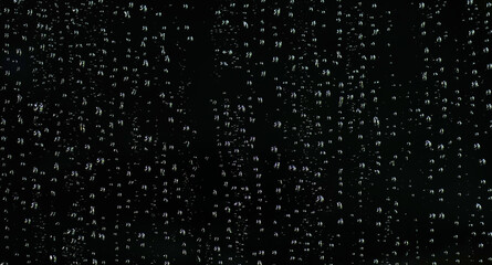 Water droplets on the black glass. Shiny water drops on black surface.
