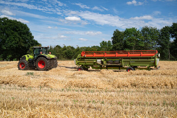 Fototapeta premium Schneidwerk für einen Mähdrescher wird mit Hilfe eines Schneidwerkstransporter und Trecker zum Mähdrescher auf ein Getreidefeld gebracht.