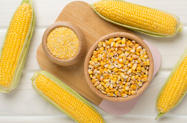 Corn groats and seeds with fresh cobs on wooden background, top view