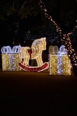 Christmas gifts and horse decorated with vertical curtains of multi-colored round lights.