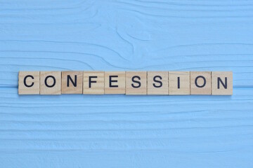 word confession made of small gray wooden letters on a blue wood background