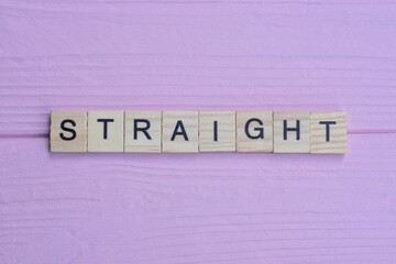 word straight from small gray wooden letters lies on a pink background