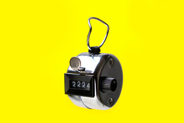 Manual mechanical counting counter on yellow background.
