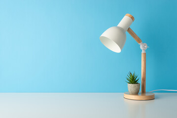 Side view photo of desk arrangement portraying table lamp, and small flowerpot with succulent...