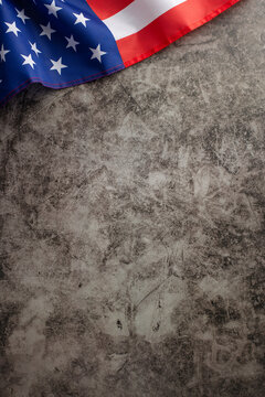 Patriotic holiday celebration: top vertical photo featuring the American flag on a grunge grey concrete background. Ample copy-space for advertisements or text placement during the public holiday