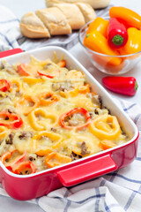 Casserole with potatoes, sausage and colorful bell pepper, in baking dish, vertical