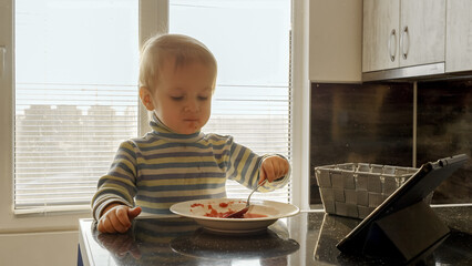 Little toddler boy got messy after eating soup by himself on kitchen