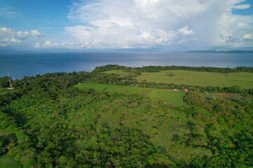 Fototapeta na wymiar AERIAL: Tropical countryside with green meadows by the coast of Pacific Ocean