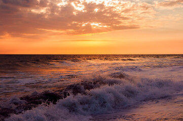 Waves on the shore of black sand beach of volcanic origin on the coast of Guatemala, sunset.