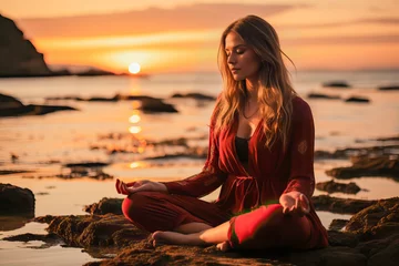 Fotobehang Strand zonsondergang A woman in a red outfit meditating peacefully on a beautiful beach