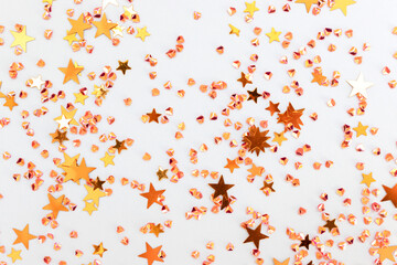 Glittering gold colored stars and crystals confetti on a blue background. Festive texture. Selective focus.