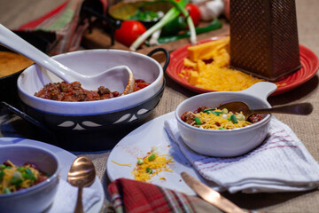 Homemade chili dinner with cornbread and ingredients.