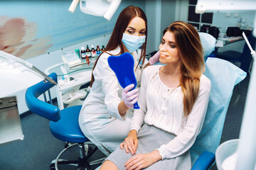 Smiling woman at reception in dental clinic during procedure. Patient at dentist examines teeth in modern clinic. Overview of caries prevention. Medicine concept. Healthy teeth.