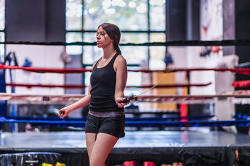 Jumping rope warm up. Sportswoman fitness training working out in boxing gym. Hispanic young woman