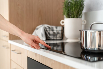 closeup of woman turn on induction stove at stylish house