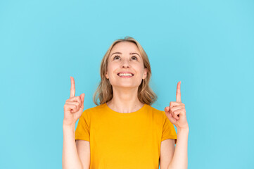 Happy woman pointing with forefingers up, on copy space for advertising