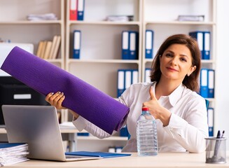 Middle-aged female employee doing exercises in the office