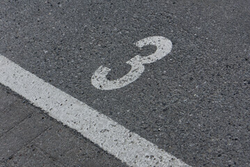 a number 3 painted on asphalt parking spot