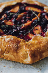 peach, blackberry, thyme galette close up on parchment paper