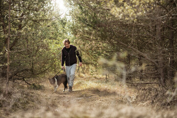 Mature man jogging in the forest with his border collie dog