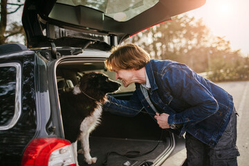 Mature man sitting in a car trunk with his dog at the park