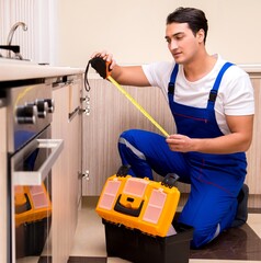 Young repairman working at the kitchen