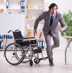 Young handsome employee in wheelchair at the office