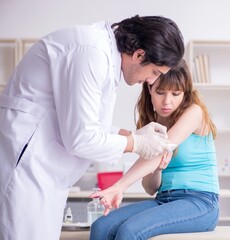 Young arm injured woman visiting young doctor traumatologist