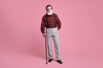 Fototapeta premium Senior man with walking cane on pink background
