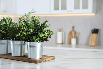 Different artificial potted herbs on white marble table in kitchen, space for text