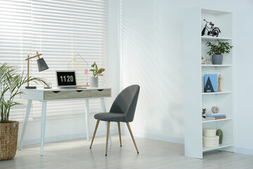 Cozy workspace with laptop, desk and comfortable chair at home. Stylish interior design