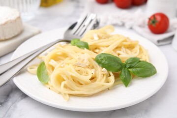 Delicious pasta with brie cheese and basil leaves on marble table, closeup